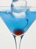 Blue Curaçao cocktail with cocktail cherry & ice cube