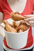 Woman holding deep-fried chicken drumsticks