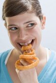 Young woman biting into deep-fried onion ring on index finger