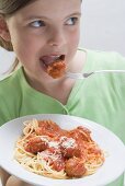 Mädchen isst Spaghetti mit Fleischklösschen
