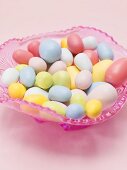 Coloured sugar eggs in pink glass dish