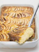 Potato gratin in baking dish with piece on server