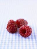 Three raspberries on checked fabric