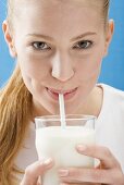 Young woman drinking milk through a straw