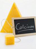 Slate board with the word Calcium in front of piece of Cheddar