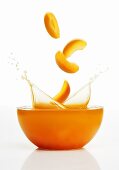 Apricot slices falling into apricot juice
