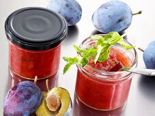 Two jars of plum jam and fresh plums