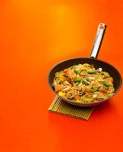 Vegetable chop suey with noodles and walnuts in frying pan