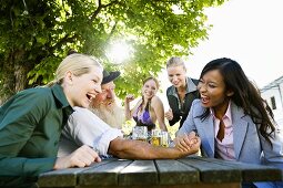 Asian woman and man in Bavarian dress in beer garden, arm wrestling