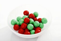 Red and green gumballs in plastic dish