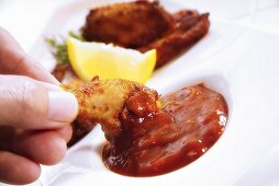 Hand dippt Chicken Wing in Barbecuesauce