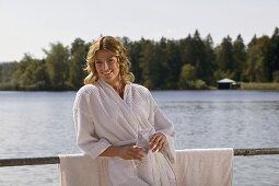 Woman wearing bathrobe, holding glass of water