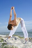 Frau macht Fitnessübung am Strand (Südafrika)