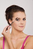 Young woman using an eyebrow pencil, portrait