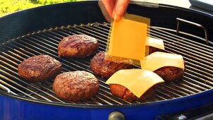Putting cheese on burgers on a barbecue (for cheeseburgers)
