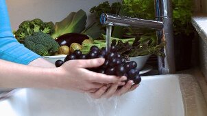 Washing red grapes under running water