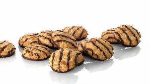 A pile of coconut macaroons with chocolate glaze and a hand taking one
