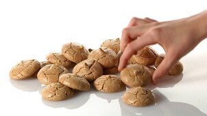 A pile of almond macaroons and a hand taking one