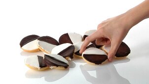A pile of black-and-white cookies and a hand taking one