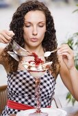 Woman pouring hot raspberries over vanilla ice cream