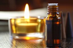 Bottle of scented oil, beside a tealight, close-up