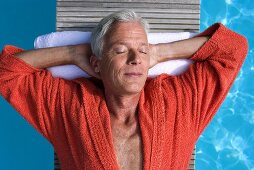 Germany, senior man relaxing on float in pool, close-up, portrait