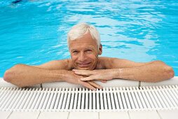 Germany, senior man relaxing in pool, close-up, portrait