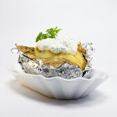 Baked potato with curd cheese in foil, close-up