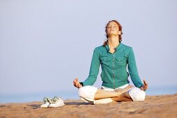 Young woman meditating on beach