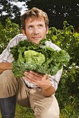 Man holding fresh savoy cabbage in garden