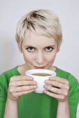 Young woman holding tea bowl, portrait