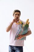 Man carrying grocery bag, eating carrot