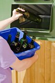 Person putting bottle into refuse container