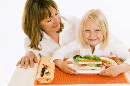 Mother & daughter sitting at table in front of vegetable terrine