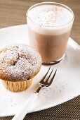 Hot cocoa and muffin with chocolate pieces and icing sugar