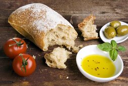 Stillleben mit Ciabatta, Olivenöl, Oliven und Tomaten