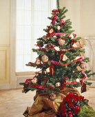 Christmas tree decorated with flowers, baubles and red silk ribbon