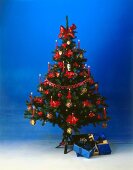 Christmas tree decorated with red plastic flowers and lit candles