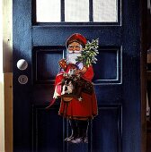 Weihnachtsmann aus Holz hängt an dunkelgrüner Tür