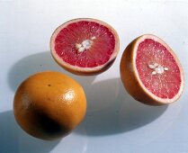 Eine ganze und eine halbierte Grapefruit freigestellt