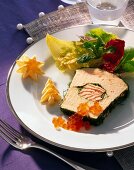 Close-up of salmon terrine with salmon caviar, lettuce and puff pastry on plate