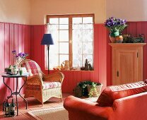 Wohnzimmer im Rot-Ton: Holzverkleidete Wände, Korbstuhl,Fliesen
