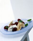 Blue grapes with yogurt and banana slices on plate