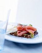 Smoked ham with radish on wholemeal bread on plate