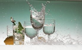 Mehrere Gläser mit Mineralwasser, auf die ein Wasserschwall platscht