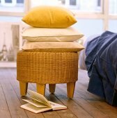 Round basket stool is used to store stack of yellow pillow