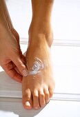 Close-up of woman's feet applying cream