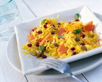 Rice and noodles with pomegranate seeds on square plate