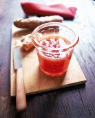 Glas mit Tomaten-Marmelade auf einem Holzbrett