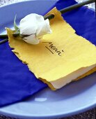 Eine weiße Rose verziert eine handgemachte Menükarte aus Büttenpapier